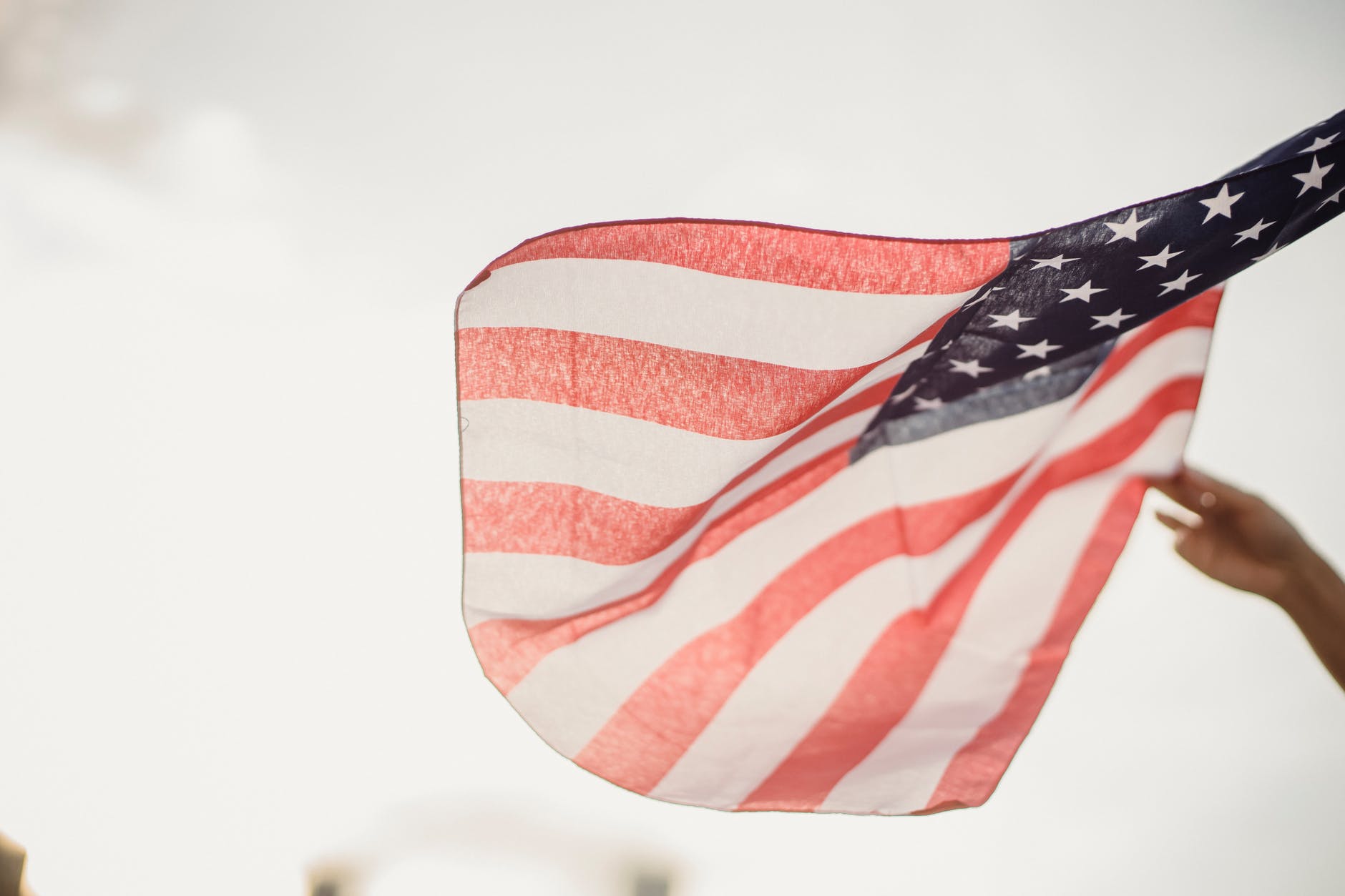 crop person holding american flag against sky