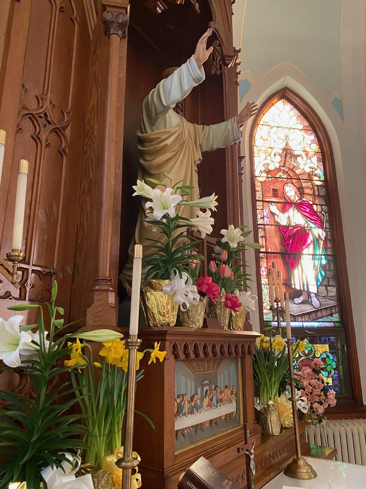 Risen Christ statue above the altar at St. John, framed by Easter lilies